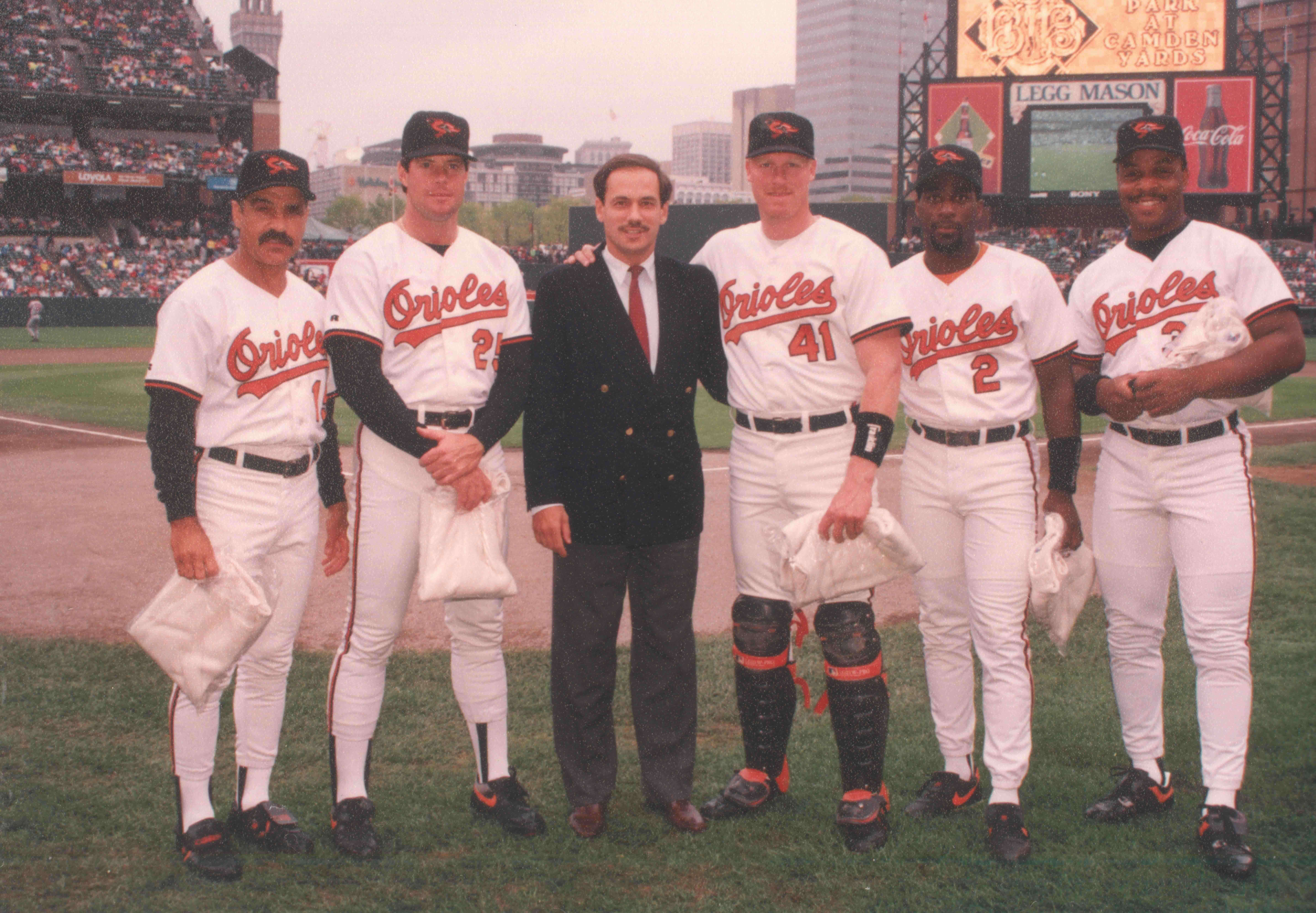 Larry Lucchino stands on the field with several Orioles players