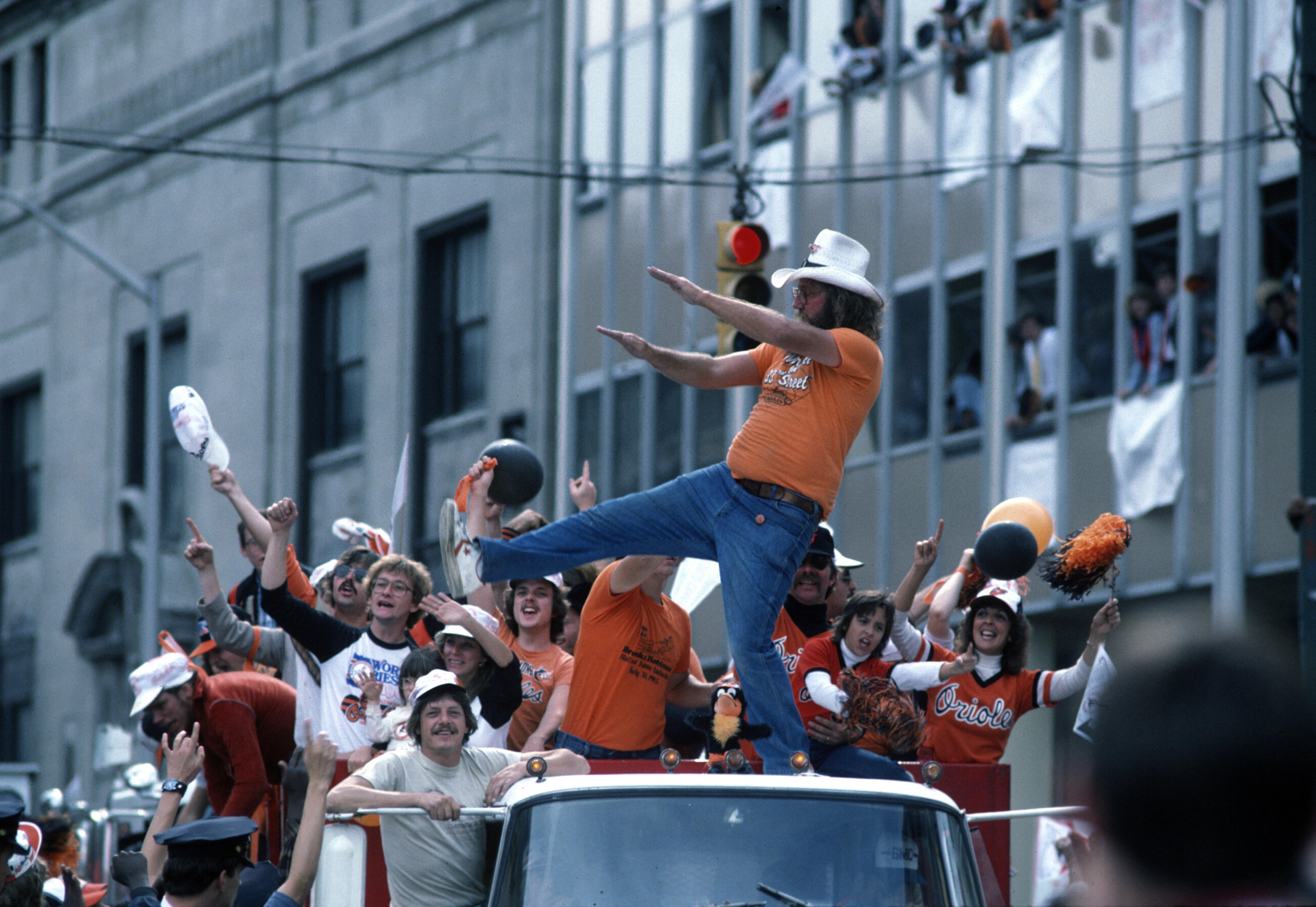 Excited fans in orange cheer from the back of a truck during parade.