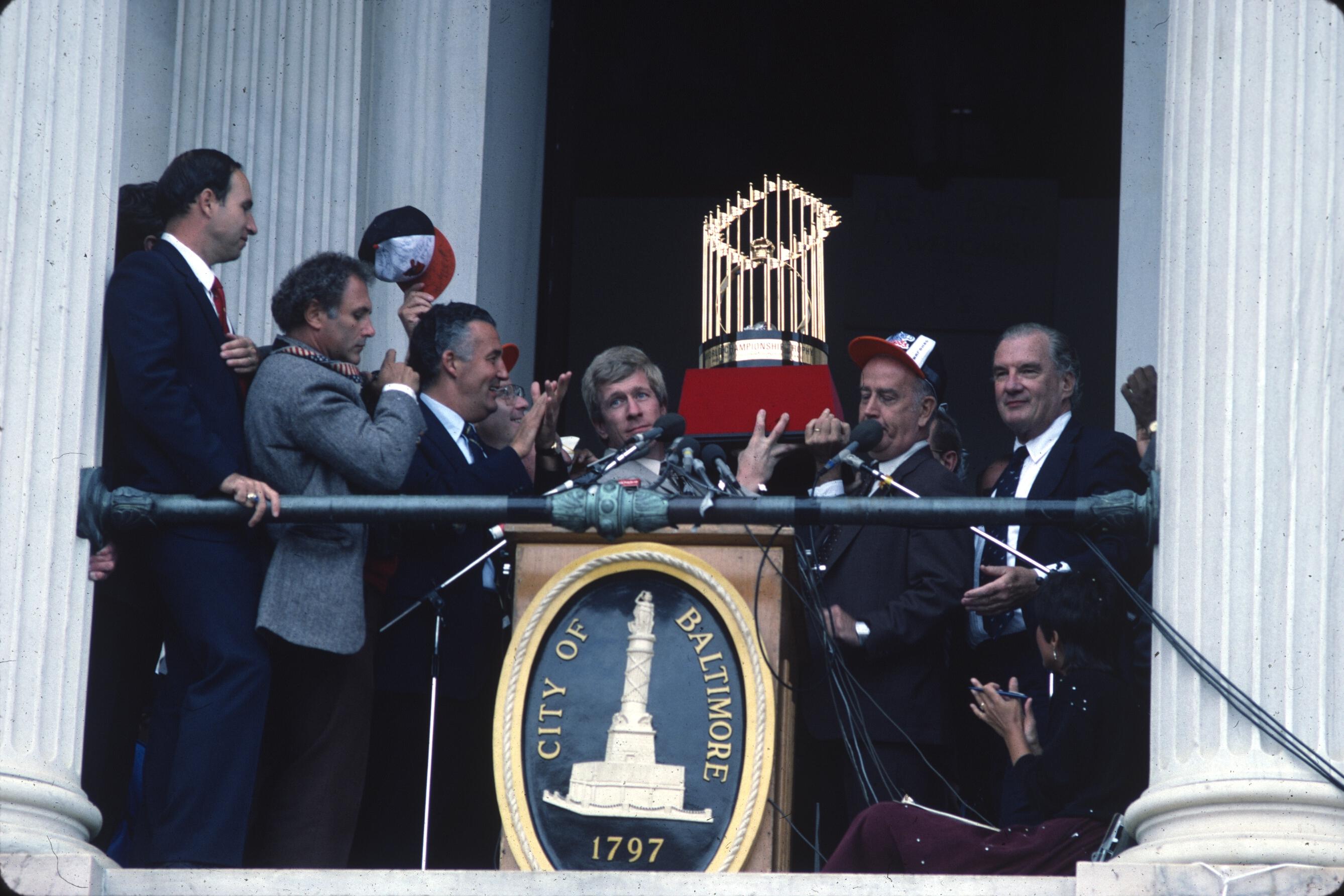 Men in suits lift the World Series trophy