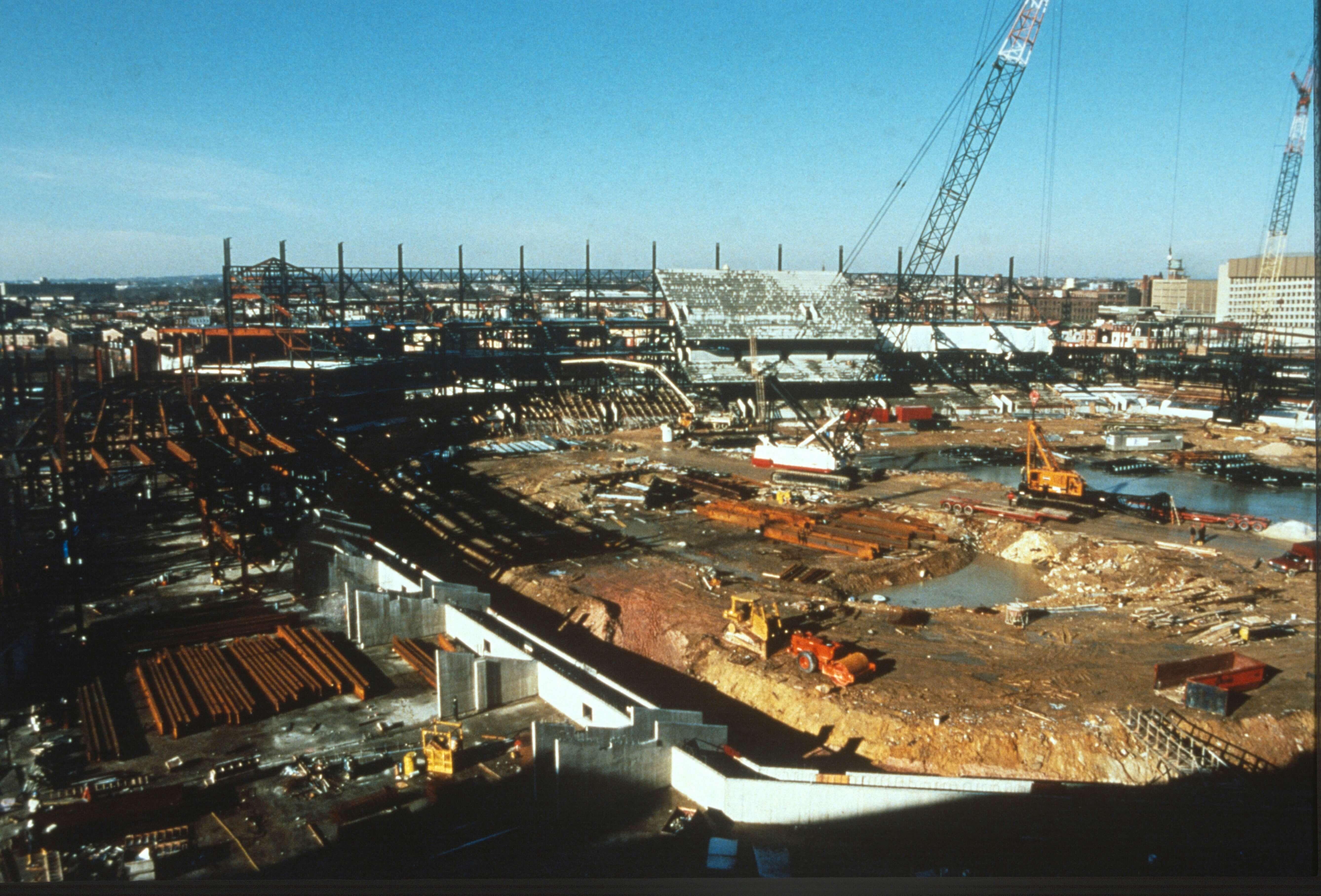 Wide view of Camden Yards construction site with cranes, steel framework, and earthmoving equipment.