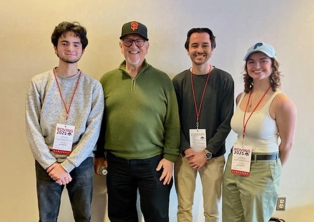 Three men and a woman standing together posing for a photo.
