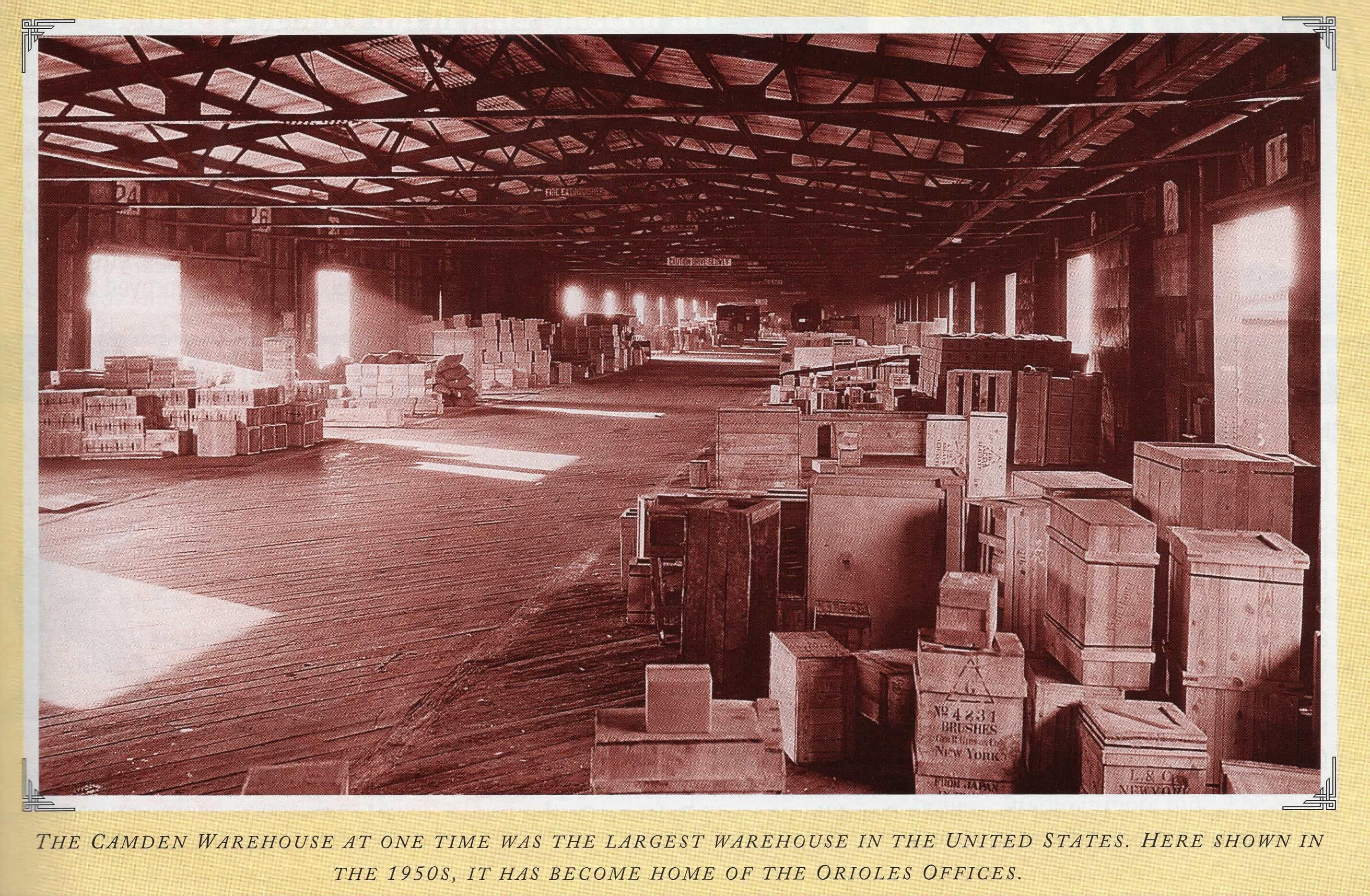 Inside a warehouse in the 1950s filled with stacked shipping crates and freight.
