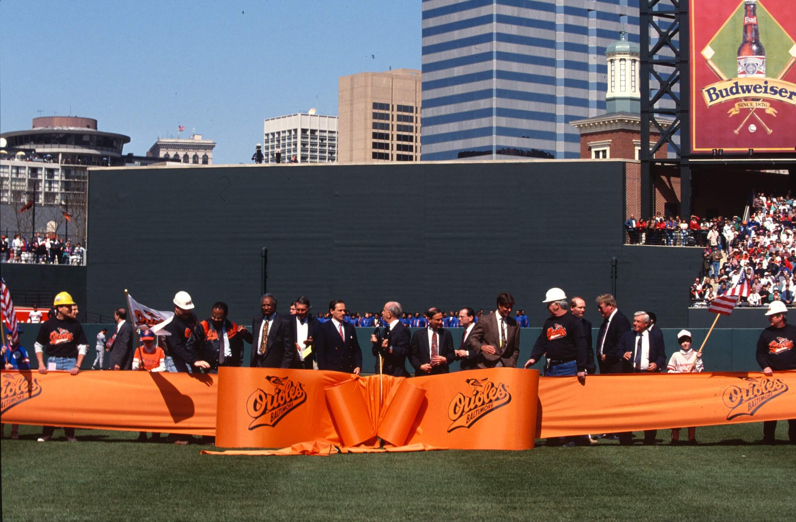 Officials and team representatives cut a large orange ribbon