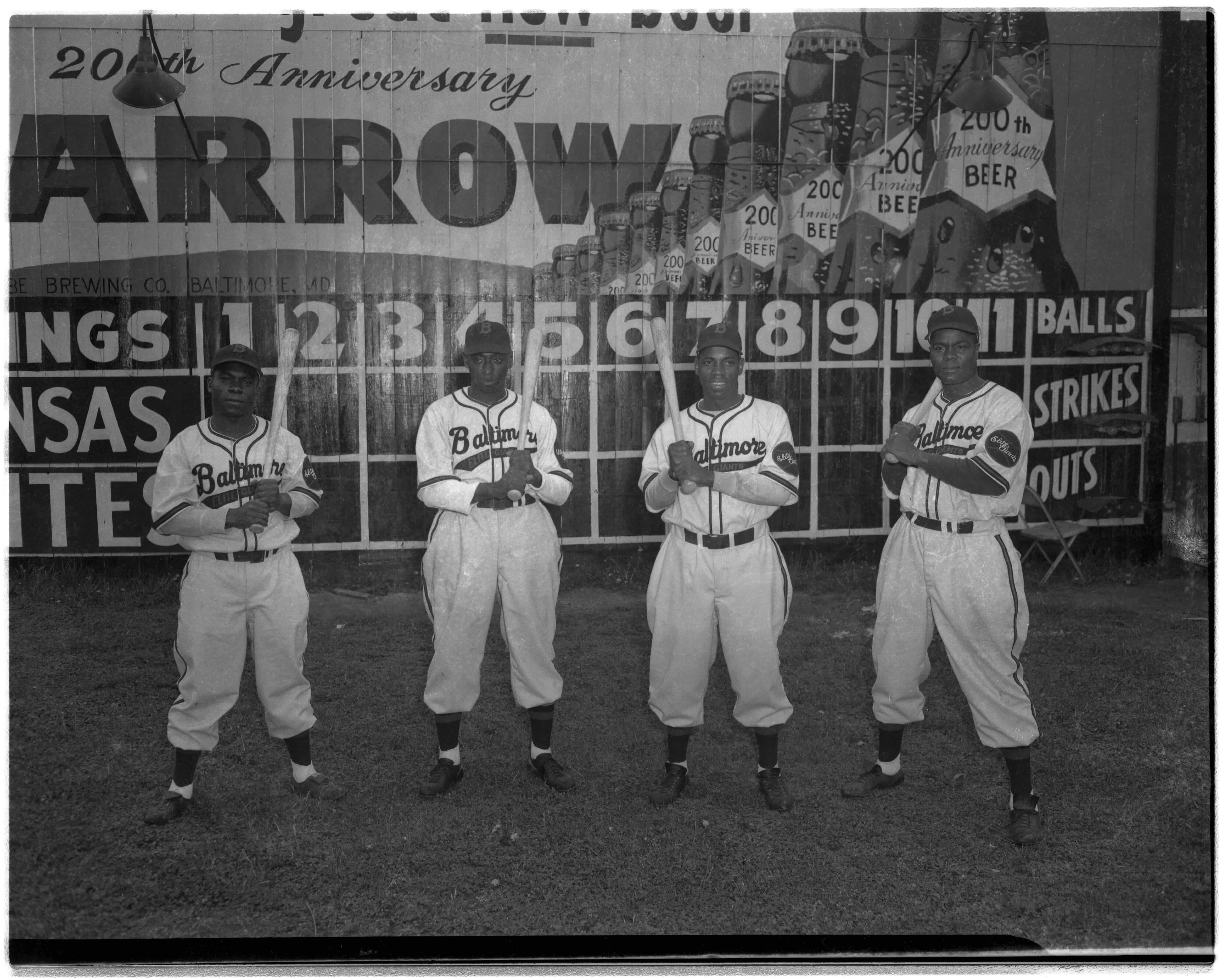 Black and white photo of four players holding baseball bats