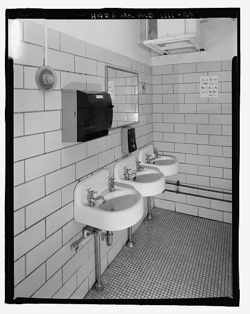 Three wall-mounted sinks and a mirror in a restroom