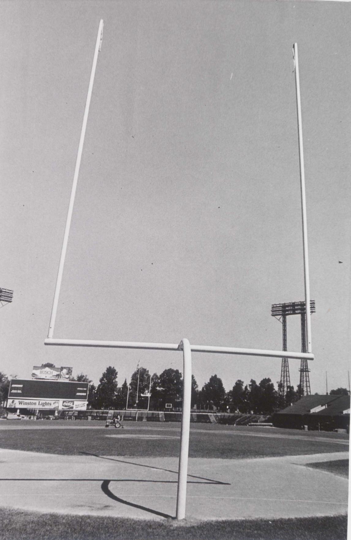 Football goalposts with empty stands and a scoreboard in the background