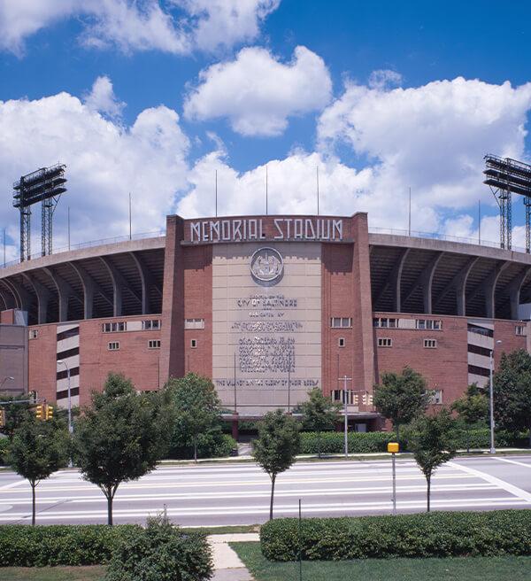 Exterior view of Memorial Stadium in Baltimore with its brick façade and “Memorial Stadium” sign above the entrance.